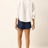 Person wearing a white shirt and navy shorts on a plain background