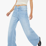 Woman wearing light blue flared jeans and a white top on a white background
