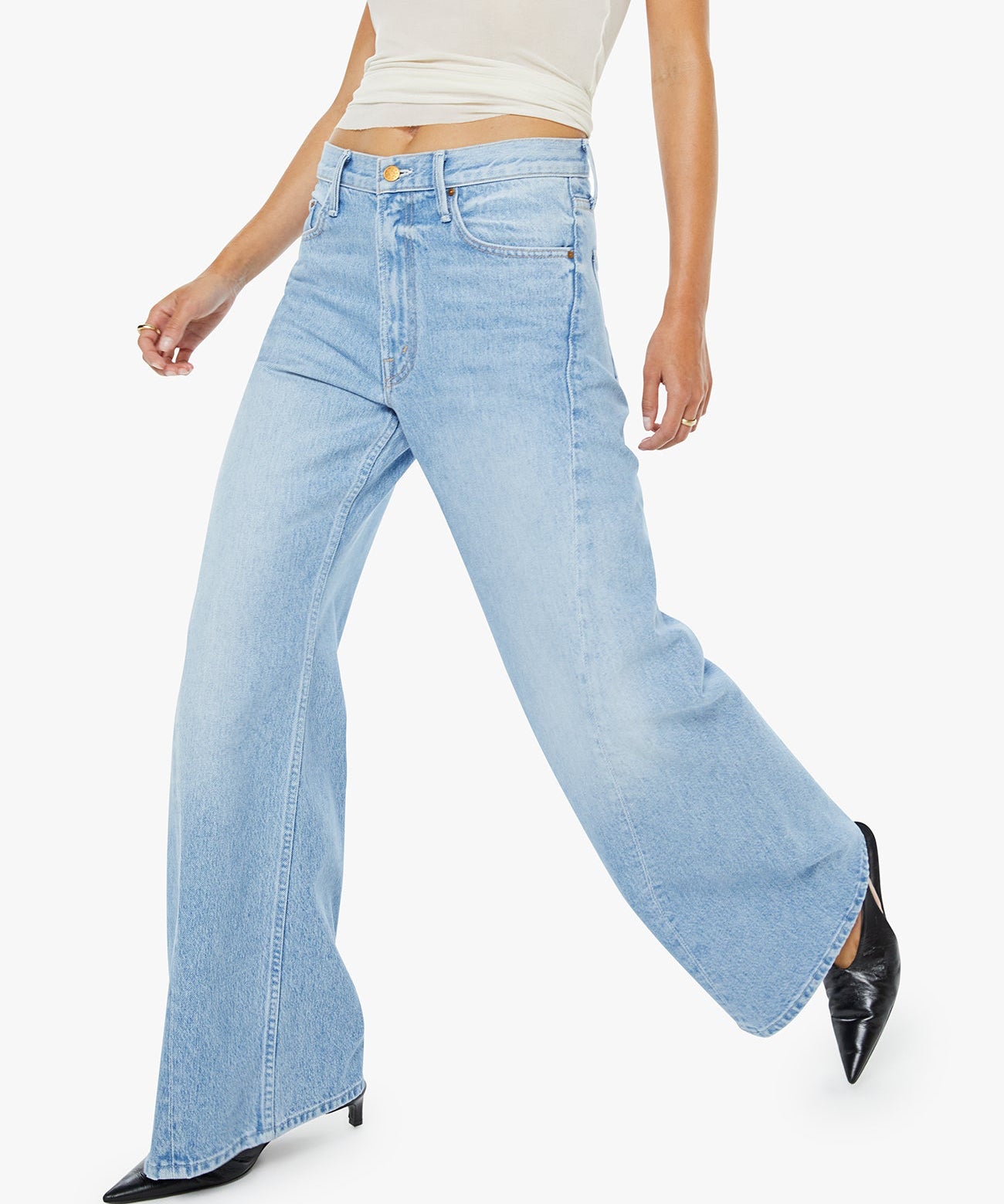 Woman wearing light blue flared jeans and a white top on a white background