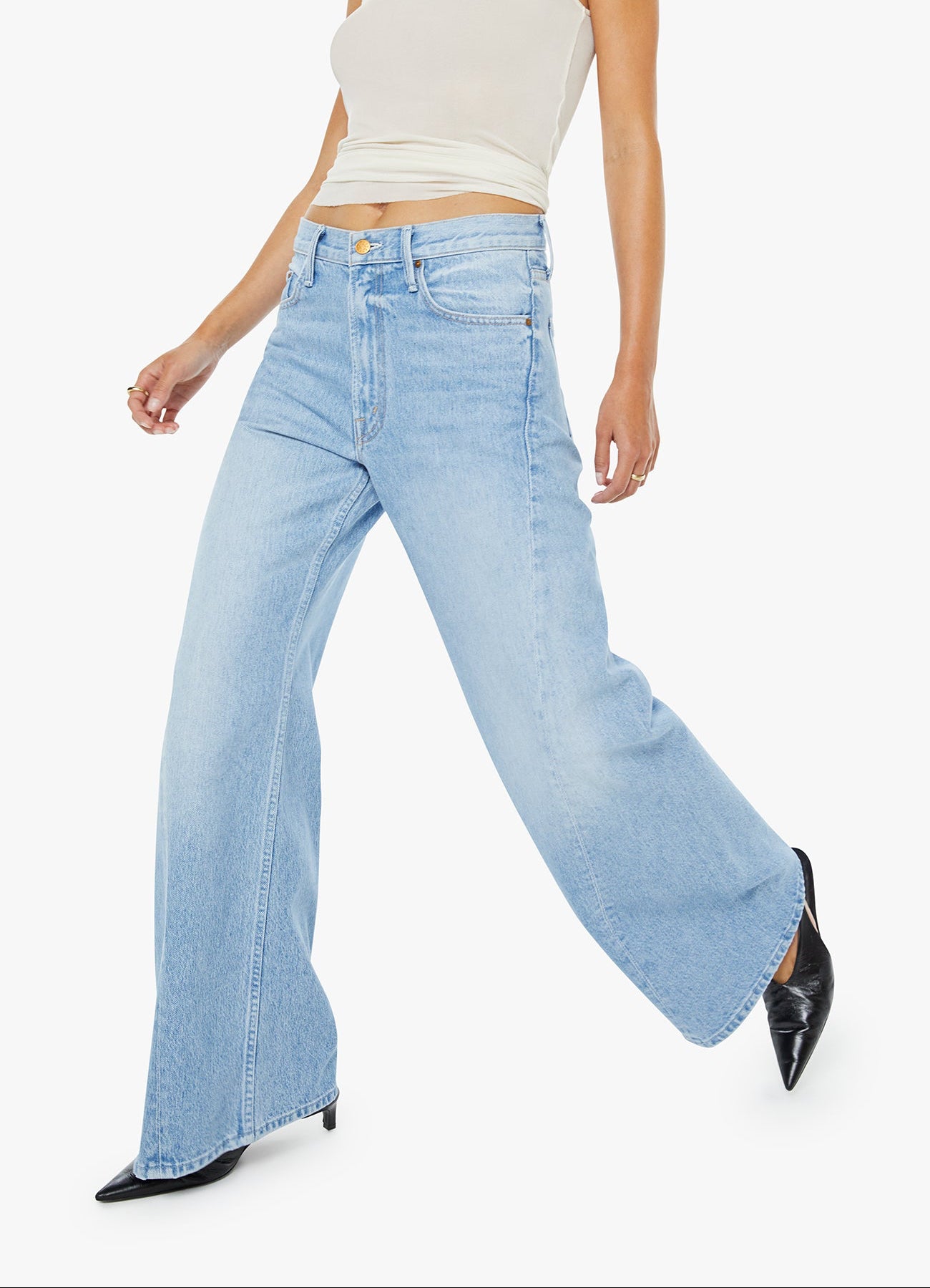 Woman wearing light blue flared jeans and a white top on a white background