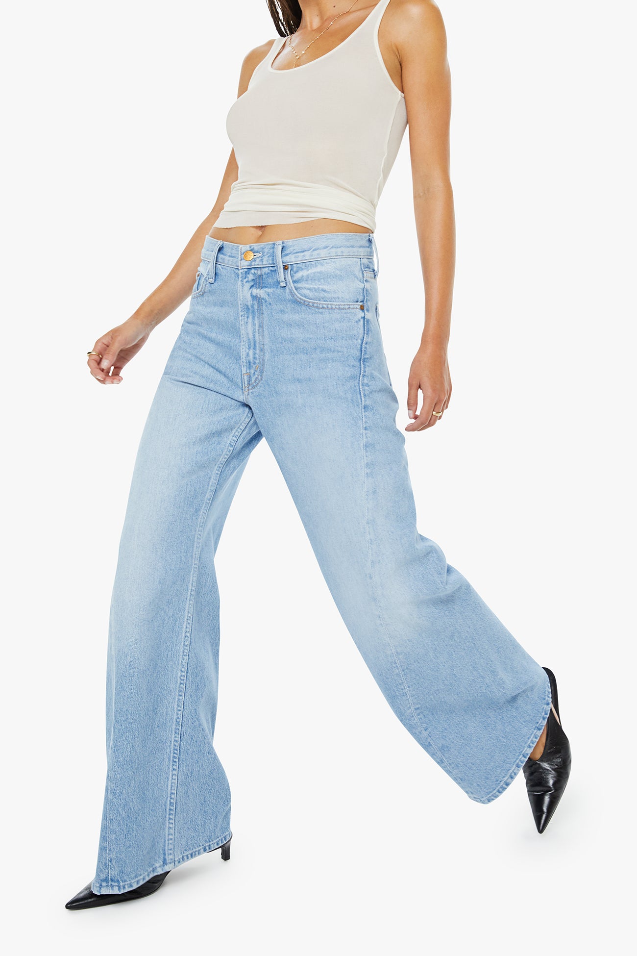 Woman wearing light blue flared jeans and a white top on a white background