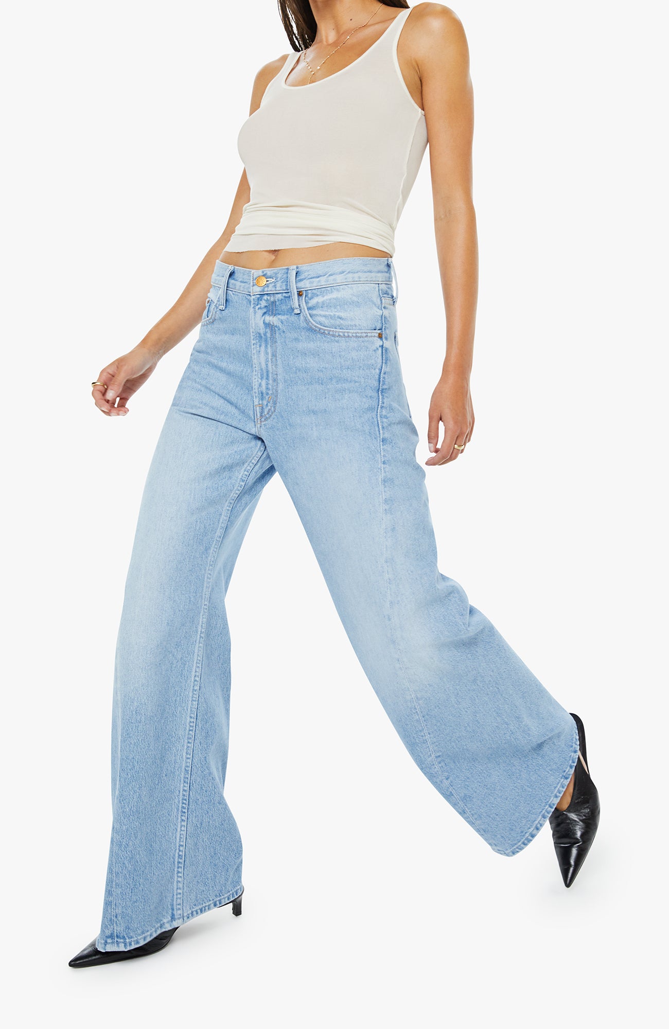 Woman wearing light blue flared jeans and a white top on a white background