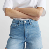 Person wearing light blue denim shorts and a white t-shirt on a plain background