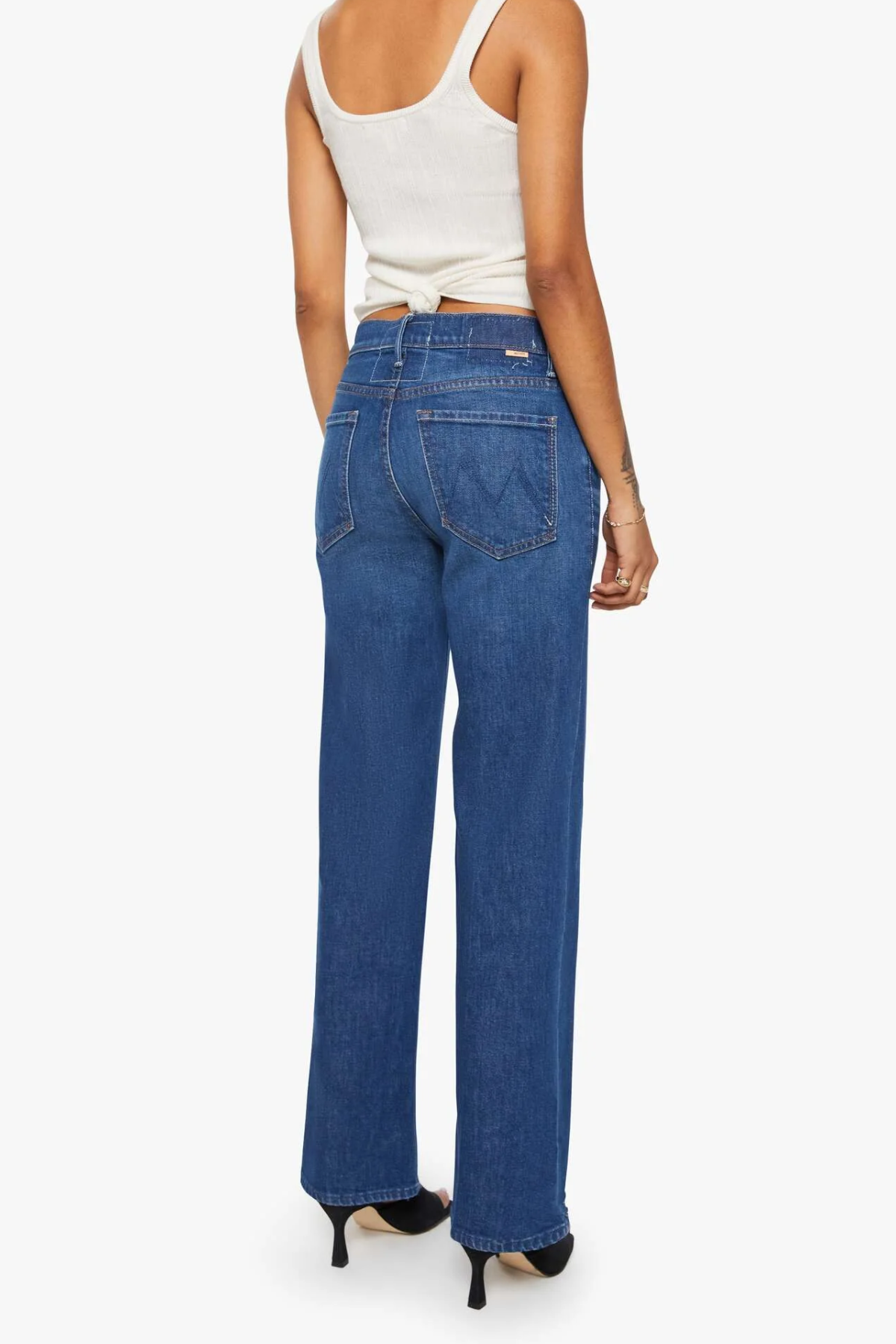 Person wearing blue jeans and a white top on a white background