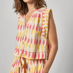 Woman wearing a sleeveless, multicolored dress against a plain background