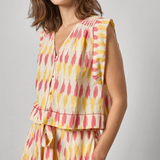 Woman wearing a sleeveless, multicolored dress against a plain background