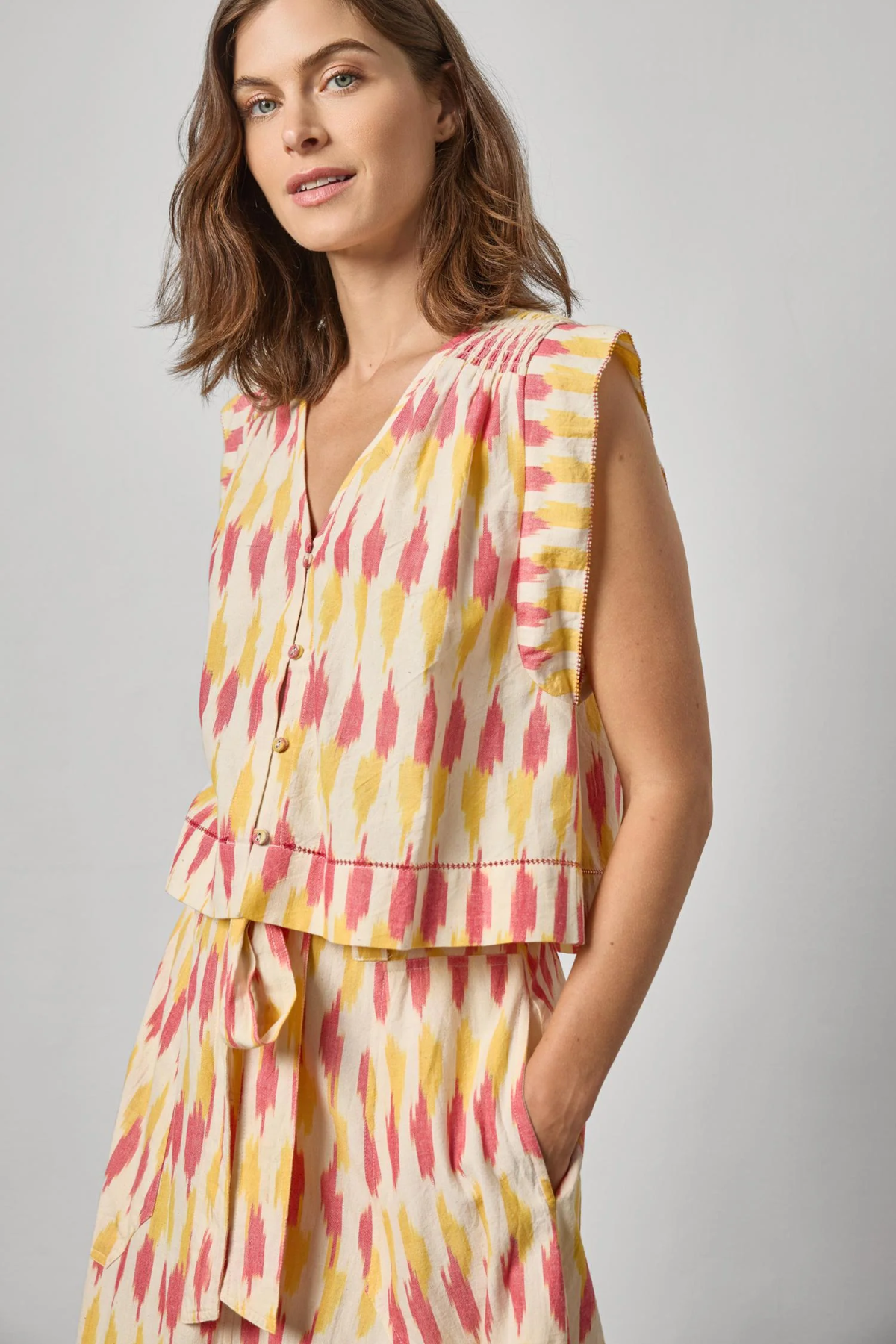 Woman wearing a sleeveless, multicolored dress against a plain background