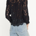 Black lace top worn by a person with light blue jeans on a white background