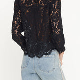 Black lace top worn by a person with light blue jeans on a white background