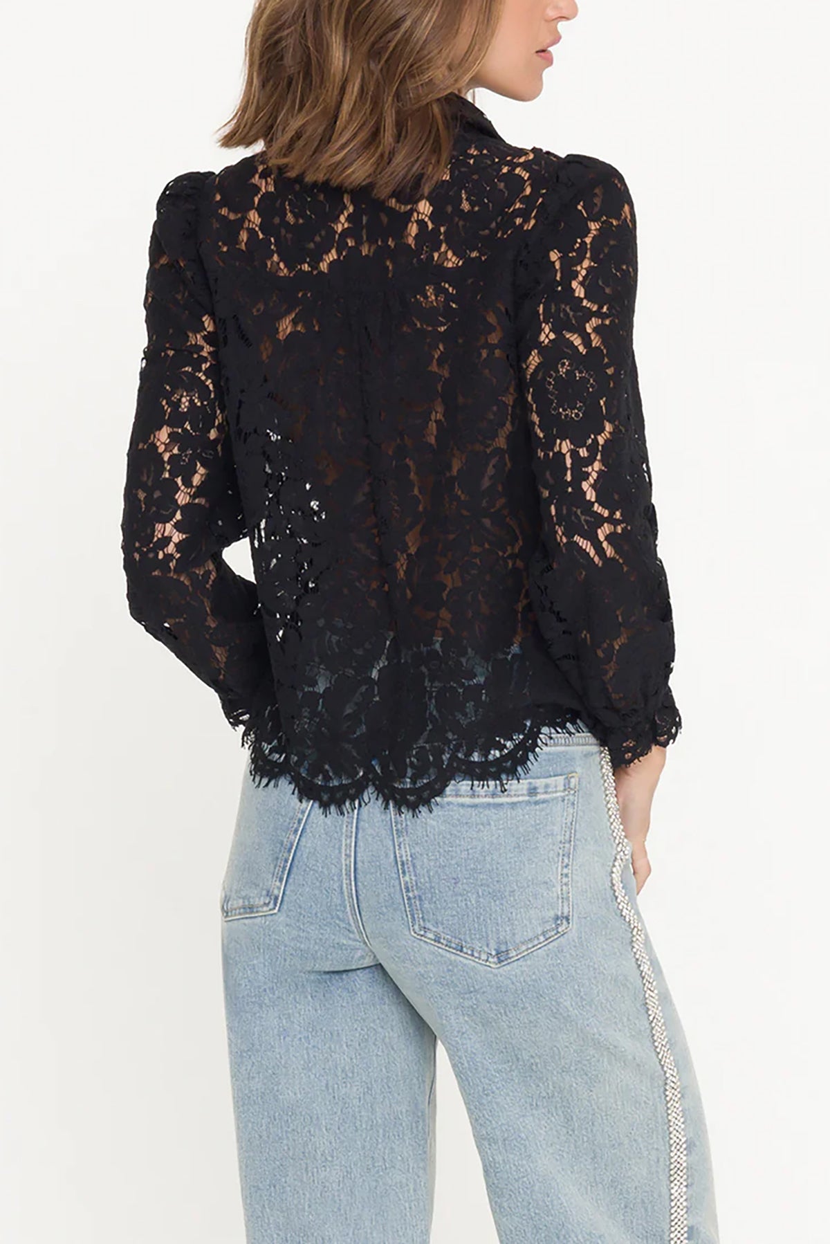 Black lace top worn by a person with light blue jeans on a white background