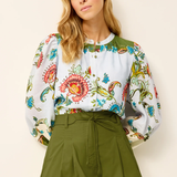 Woman wearing a floral blouse and green skirt against a plain background