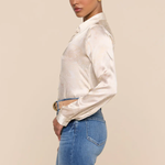 Woman wearing a white blouse and blue jeans against a beige background