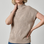 A woman wearing a beige ribbed knit mock-neck sweater vest with short sleeves, paired with blue jeans, against a light gray studio background.