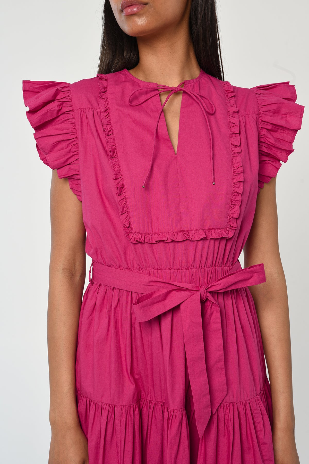 Woman wearing a vibrant pink sleeveless midi dress with soft tailoring and fluid drape.