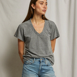 Woman wearing a gray t-shirt and blue jeans against a plain background
