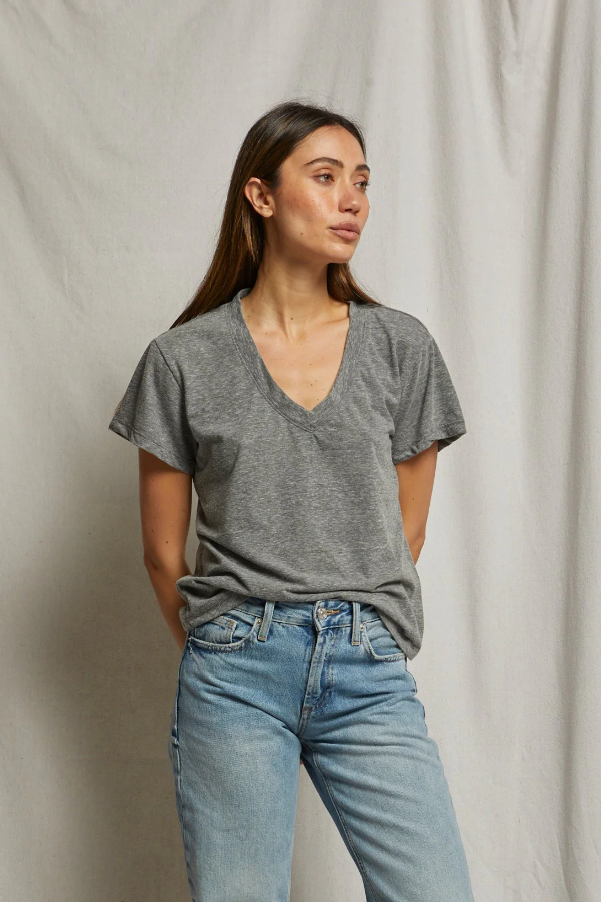 Woman wearing a gray t-shirt and blue jeans against a plain background