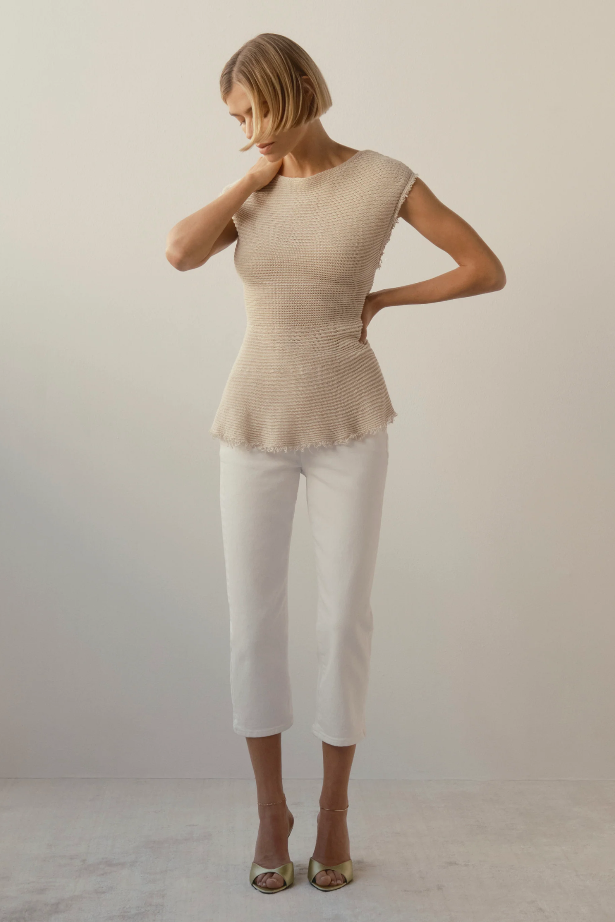 woman in tan and white outfit on white background 