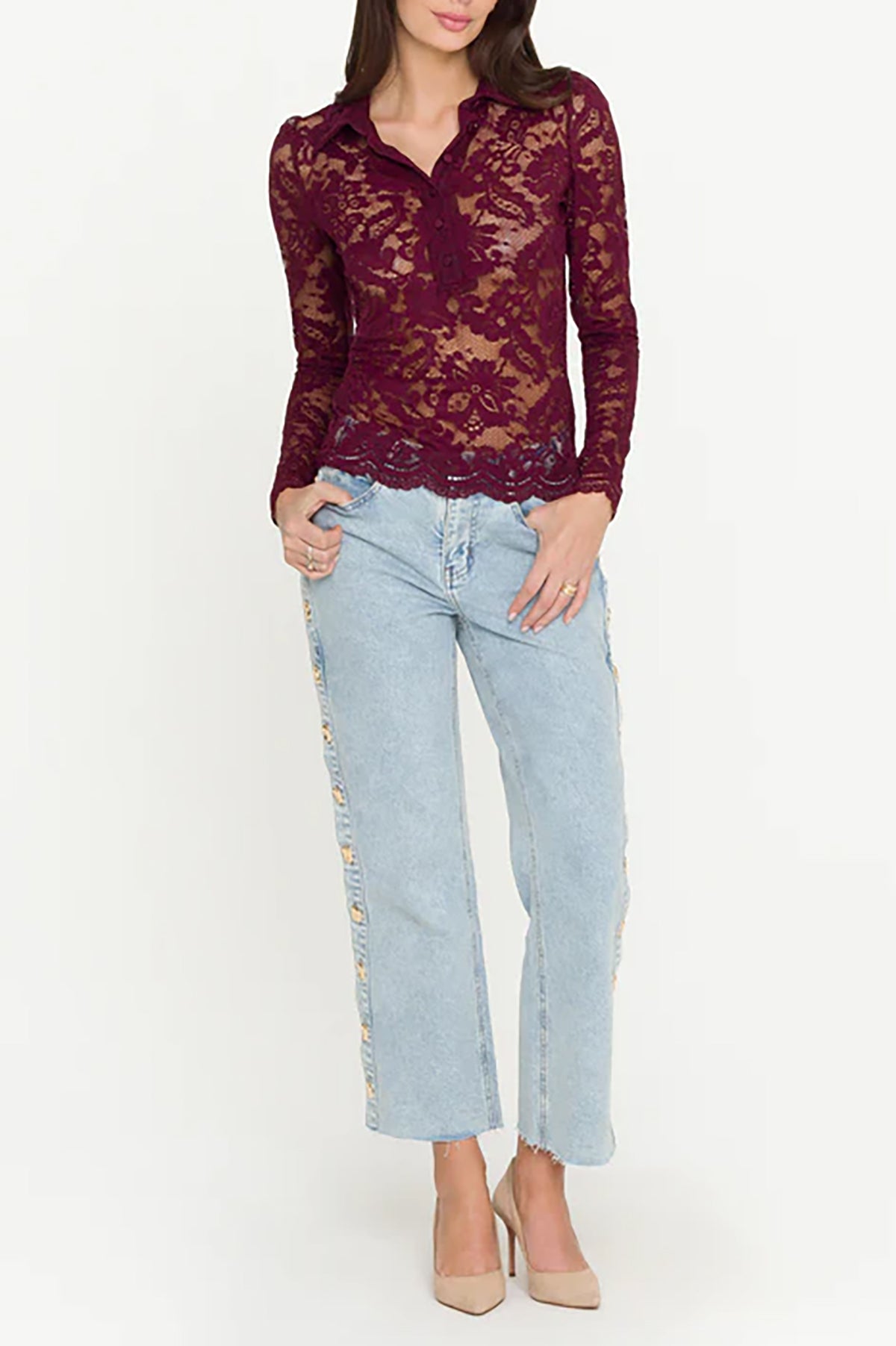 Woman wearing a burgundy lace top and light blue jeans on a white background