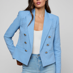 Woman wearing a light blue blazer and jeans on a gray background