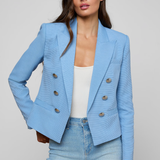 Woman wearing a light blue blazer and jeans on a gray background