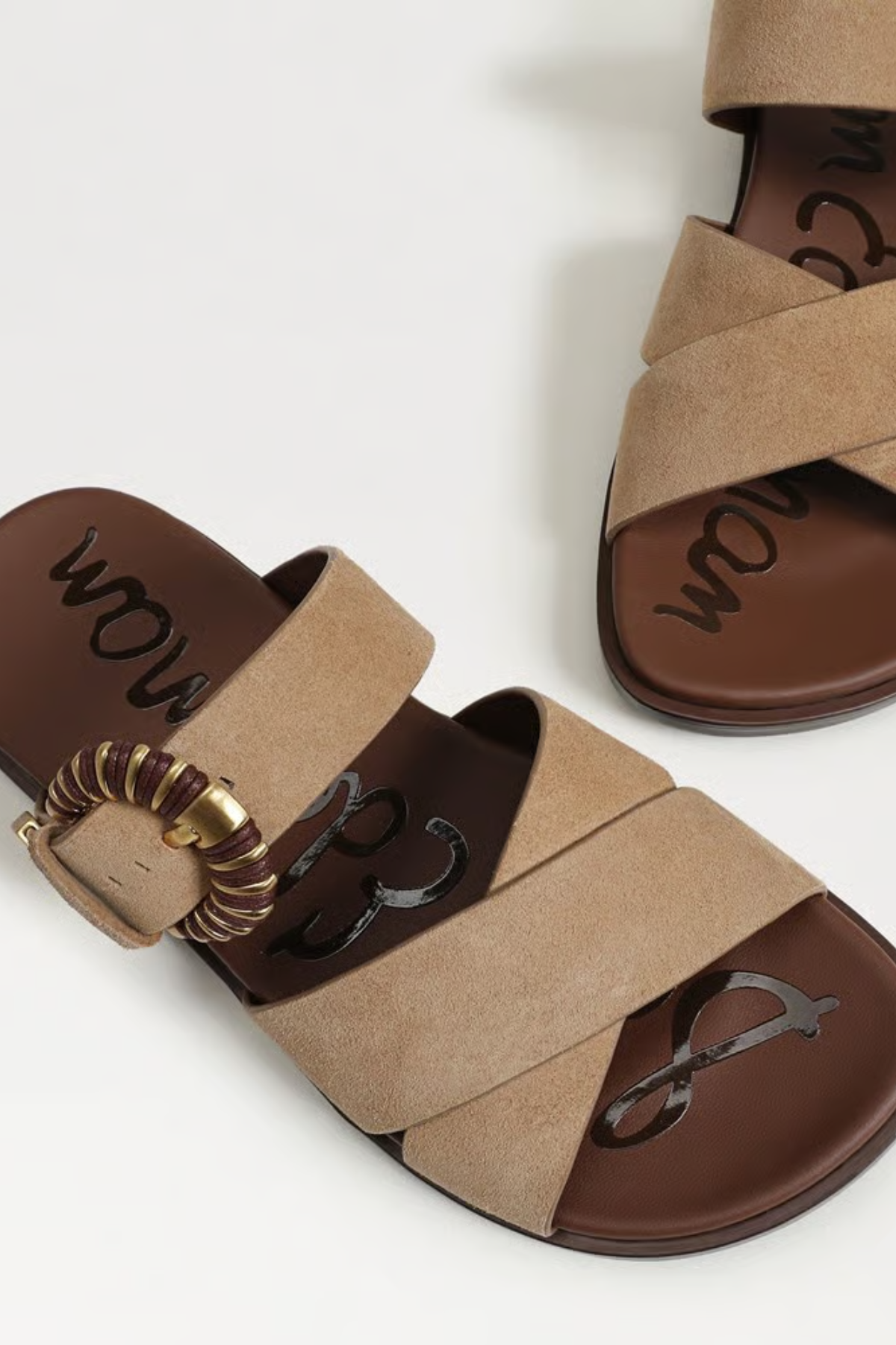 Pair of brown sandals with decorative straps on a white background