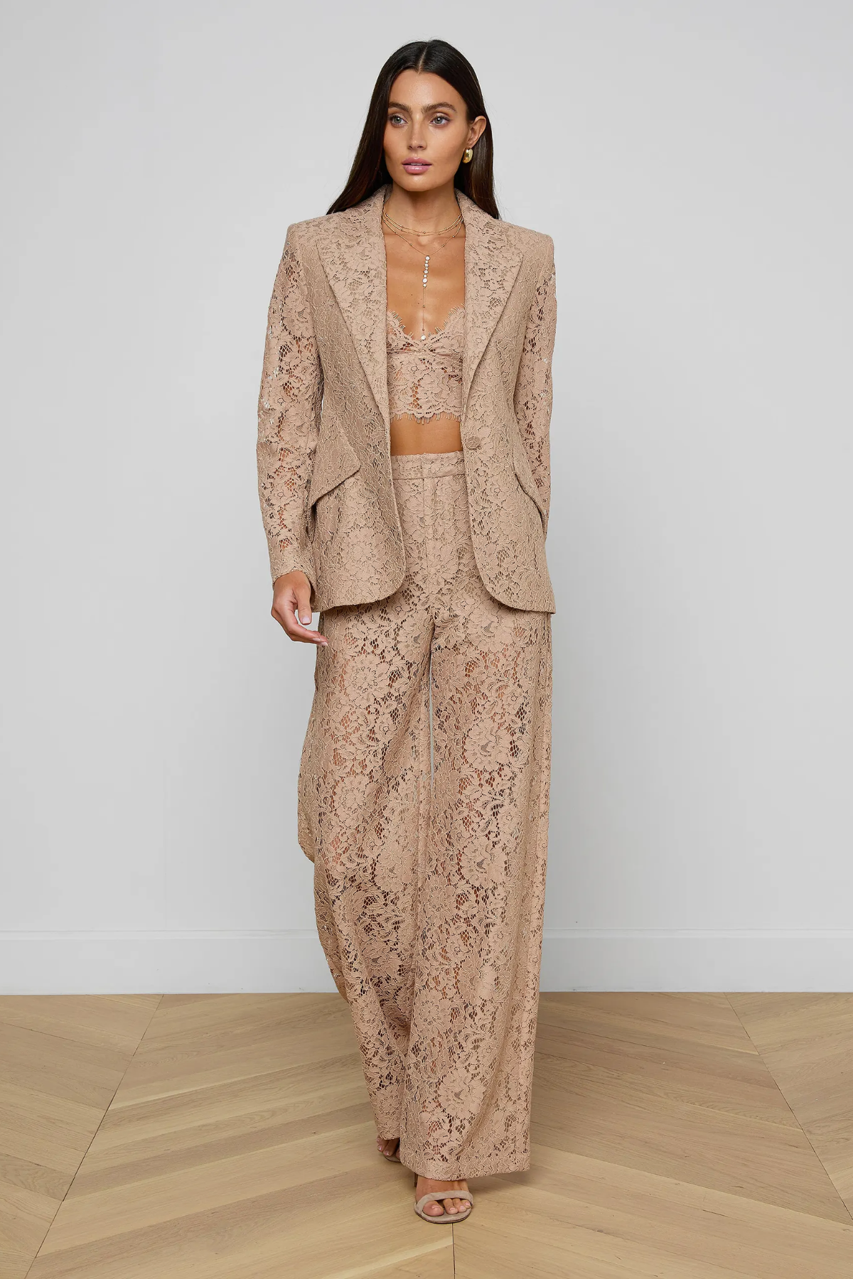 Woman wearing a beige lace outfit on a plain background