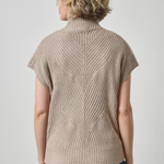A woman shown from the back wearing a beige short-sleeve ribbed knit mock neck sweater and blue jeans against a light gray studio background.