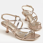 Pair of rose gold strappy high-heeled sandals on a white background