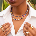 Woman wearing a colorful beaded necklace and gold jewelry outdoors