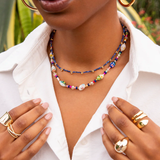 Woman wearing a colorful beaded necklace and gold jewelry outdoors