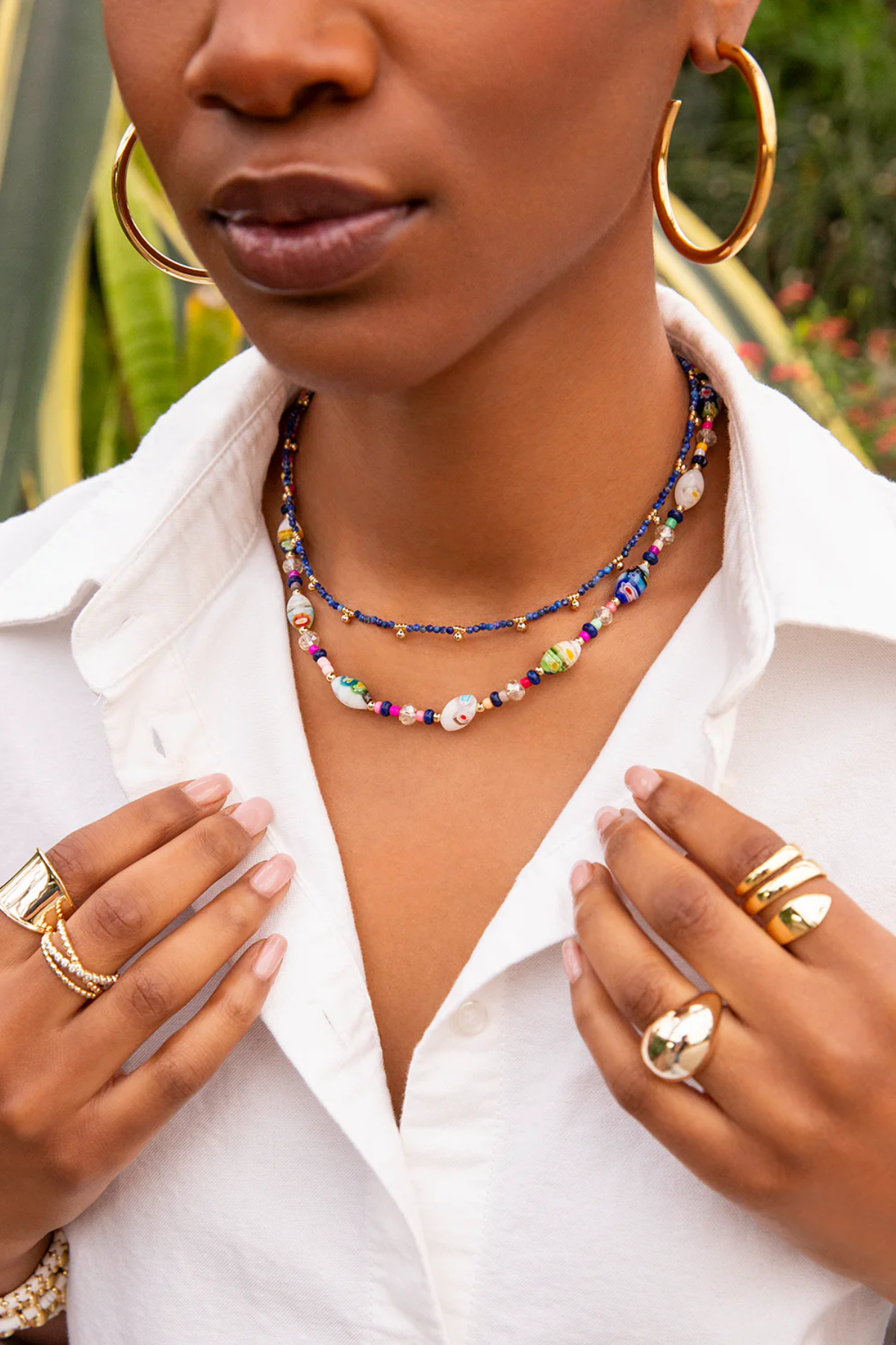 Woman wearing a colorful beaded necklace and gold jewelry outdoors