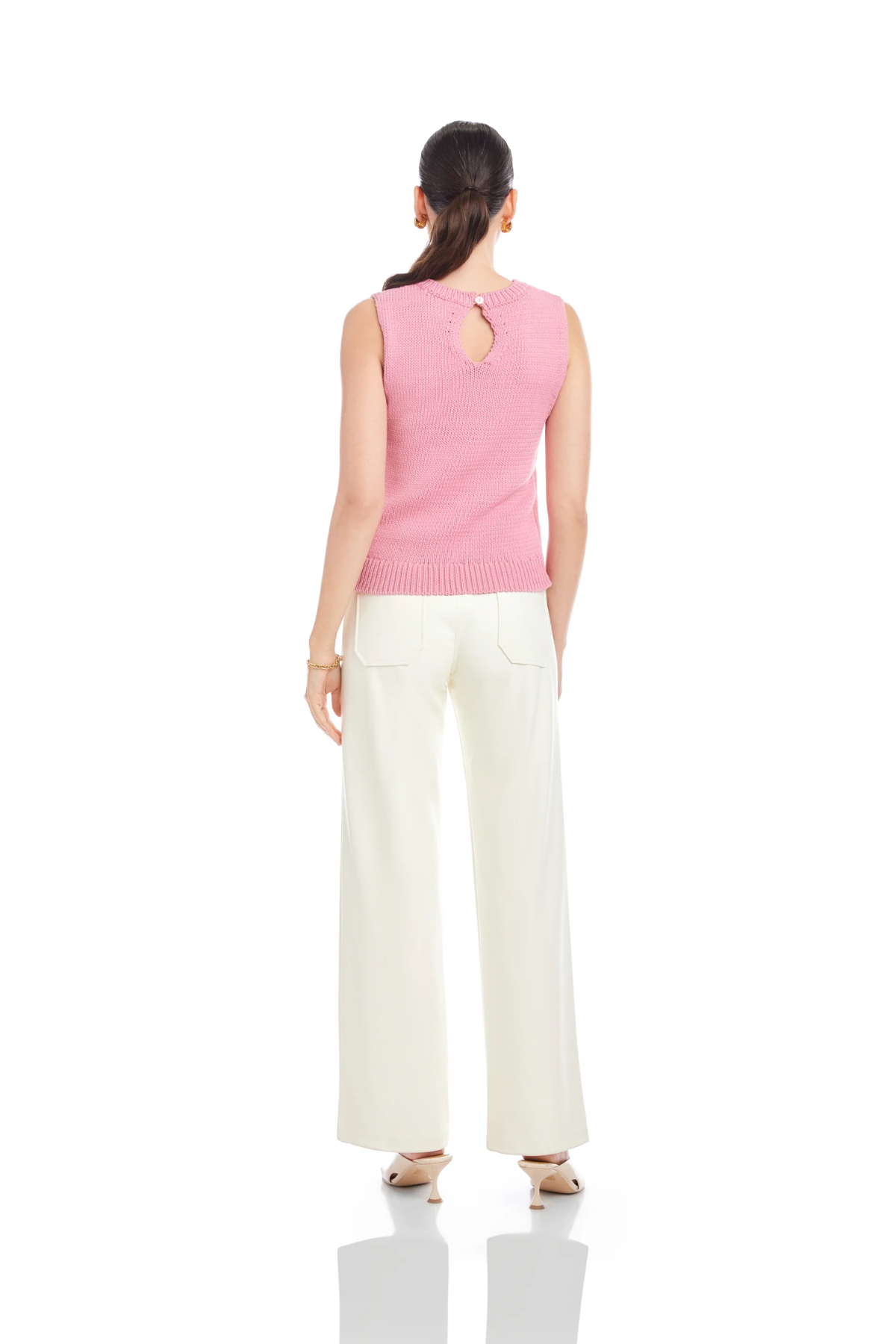 Woman wearing a pink sleeveless top and white pants on a white background
