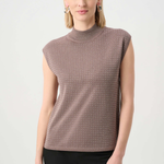 Woman wearing a sleeveless patterned top against a white background