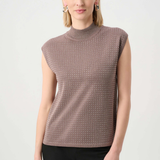 Woman wearing a sleeveless patterned top against a white background