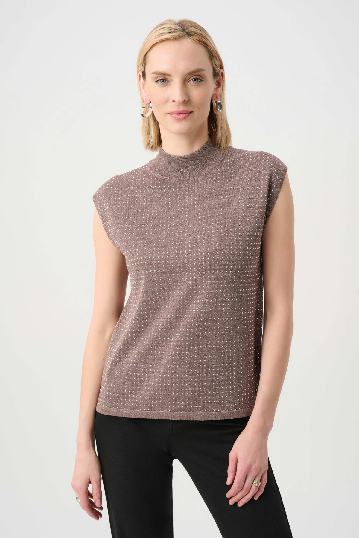 Woman wearing a sleeveless patterned top against a white background