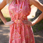 Woman wearing a pink floral dress with a blurred natural background