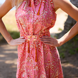 Woman wearing a pink floral dress with a blurred natural background