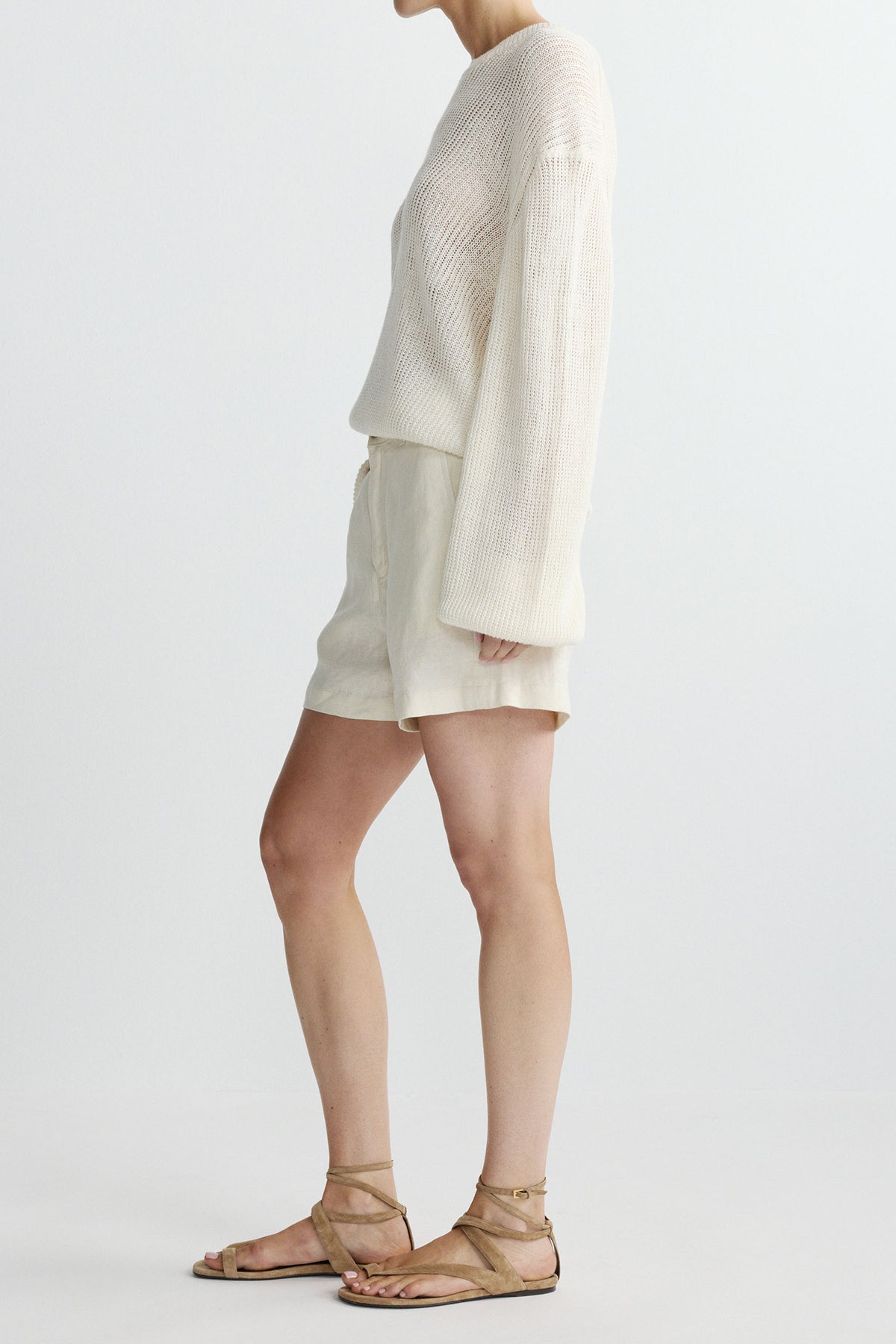 side view of woman in white sweater and shorts on white background 