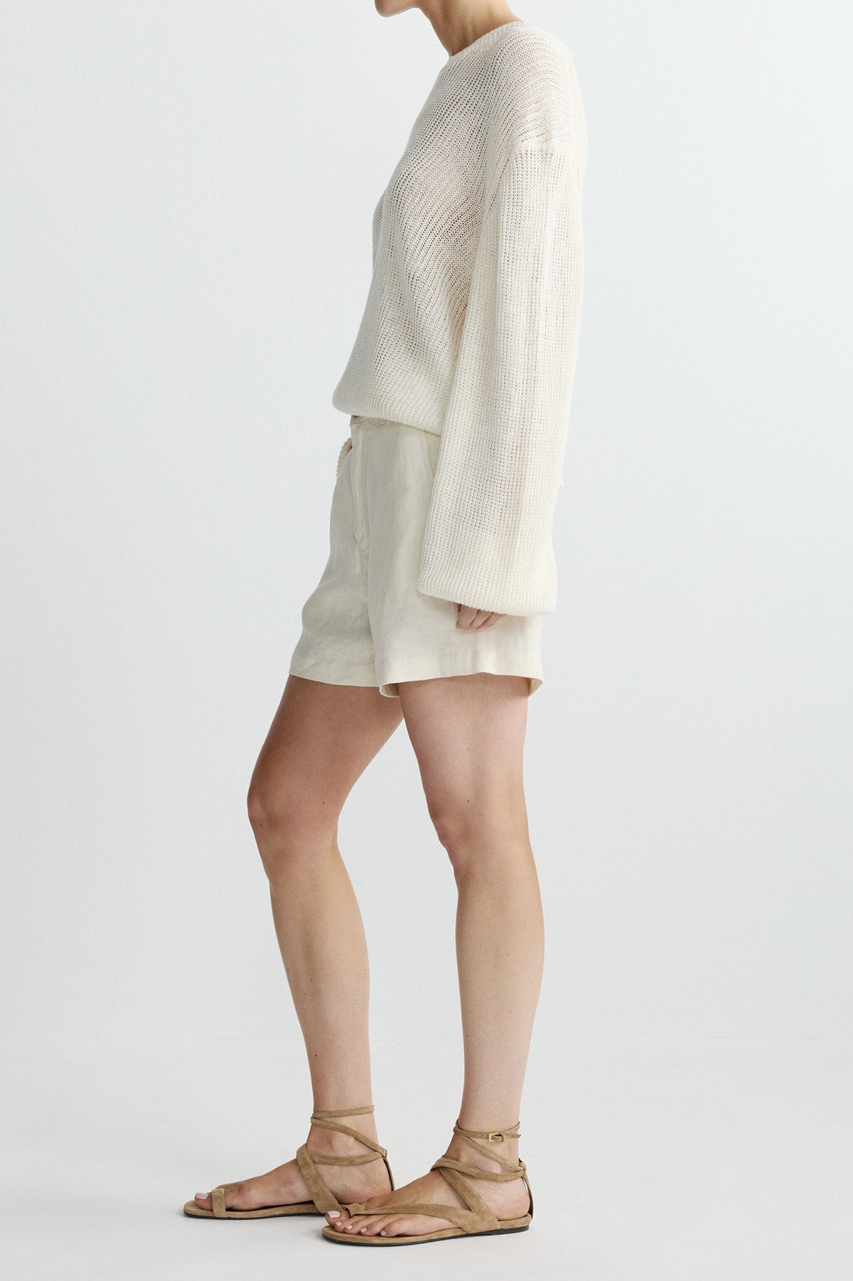 side view of woman in white sweater and shorts on white background 