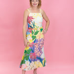 Woman wearing a colorful floral dress against a pink background