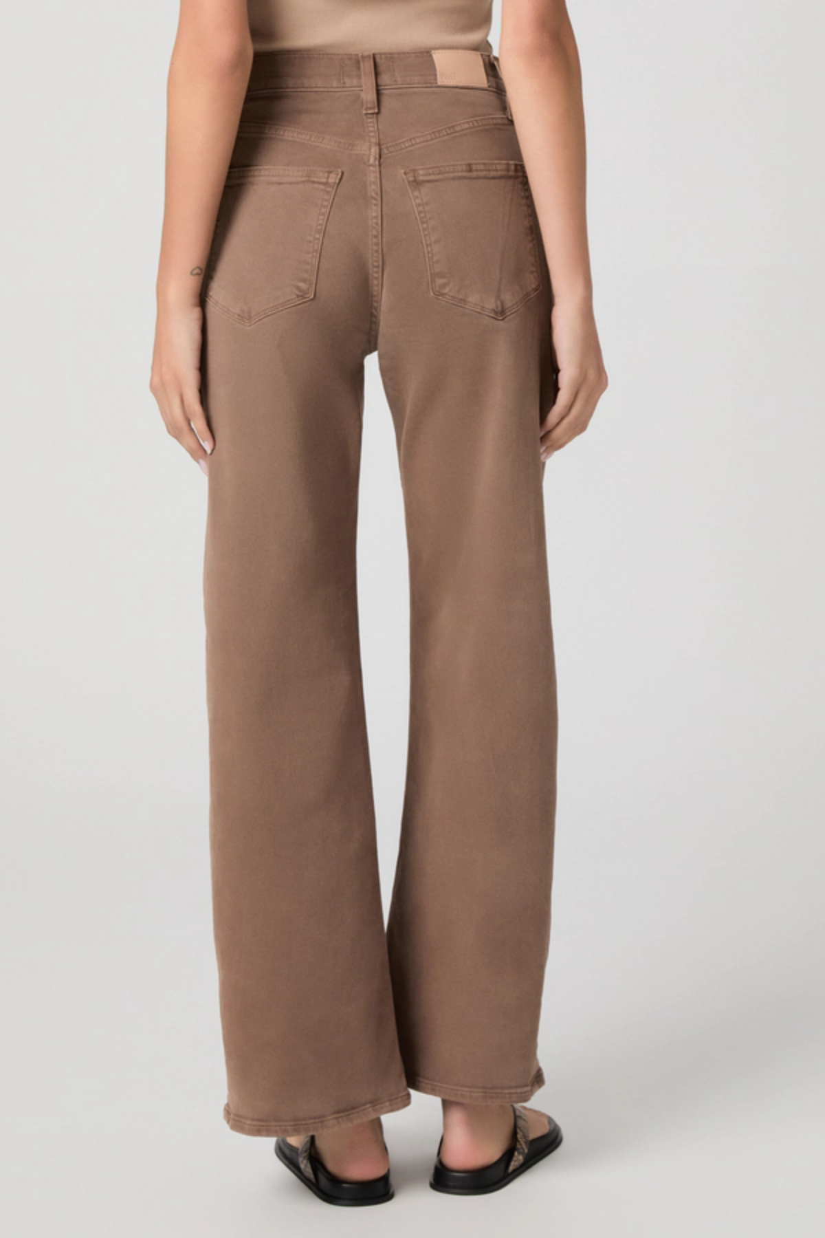 Person wearing brown wide-leg pants on a plain background