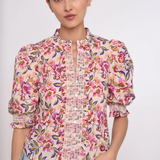 Woman wearing a floral blouse with puffed sleeves on a white background