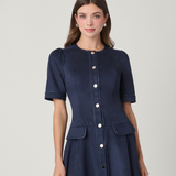 Woman wearing a navy blue dress with buttons on a light gray background