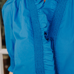 Close-up of a blue blouse with ruffled details