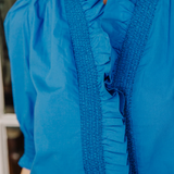 Close-up of a blue blouse with ruffled details
