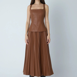 Model wearing faux leather skirt and top on gray background.