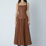 Model wearing faux leather skirt and top on gray background.