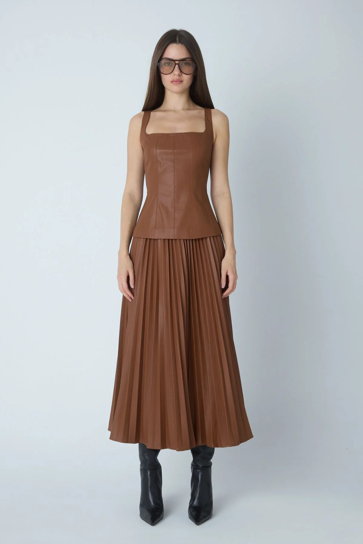 Model wearing faux leather skirt and top on gray background.