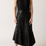 Person wearing a black sleeveless top and black leather skirt on a white background