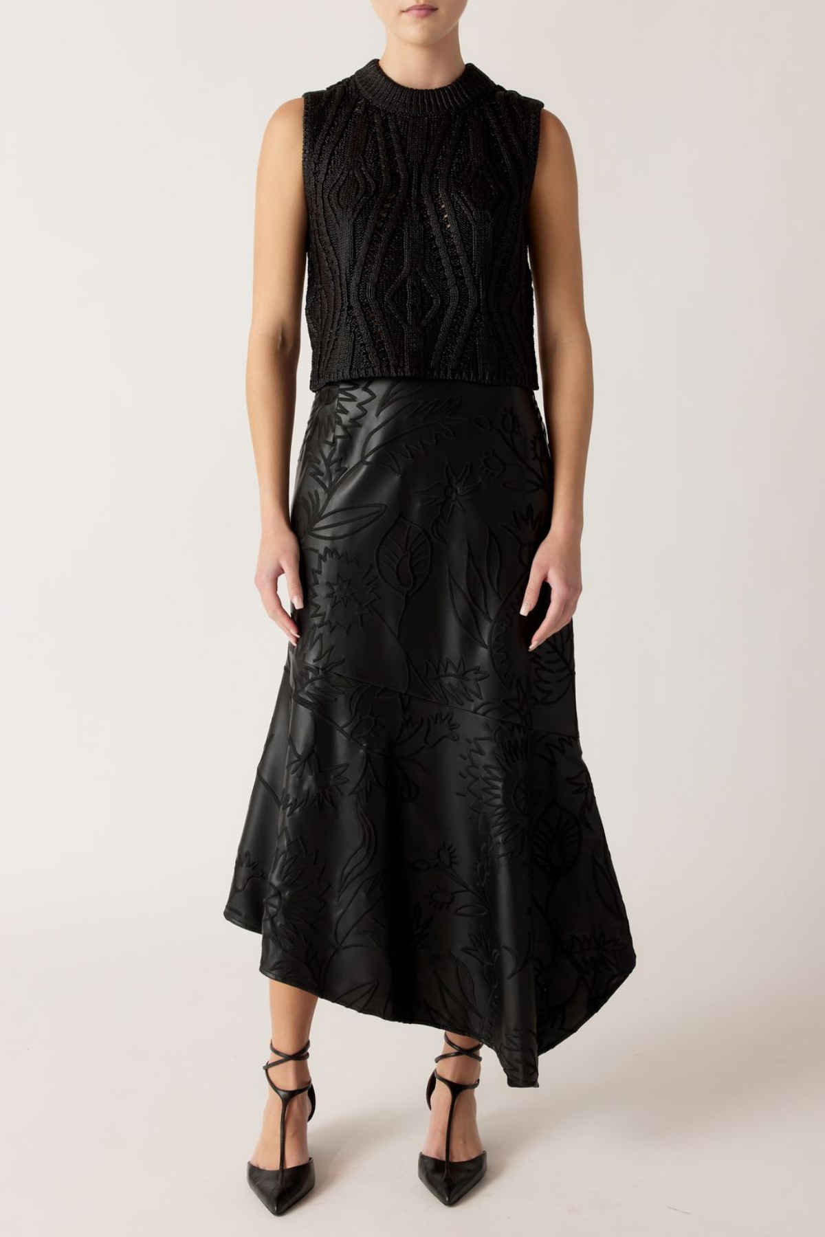 Person wearing a black sleeveless top and black leather skirt on a white background